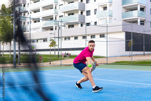 man playing pickleball game, hitting pickleball ball with paddle, outdoor sport leisure activity. © ivan