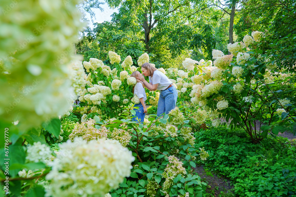 mother and daughter in flowering hydrangea bushes. mother and daughter in flowering hydrangea bushes.