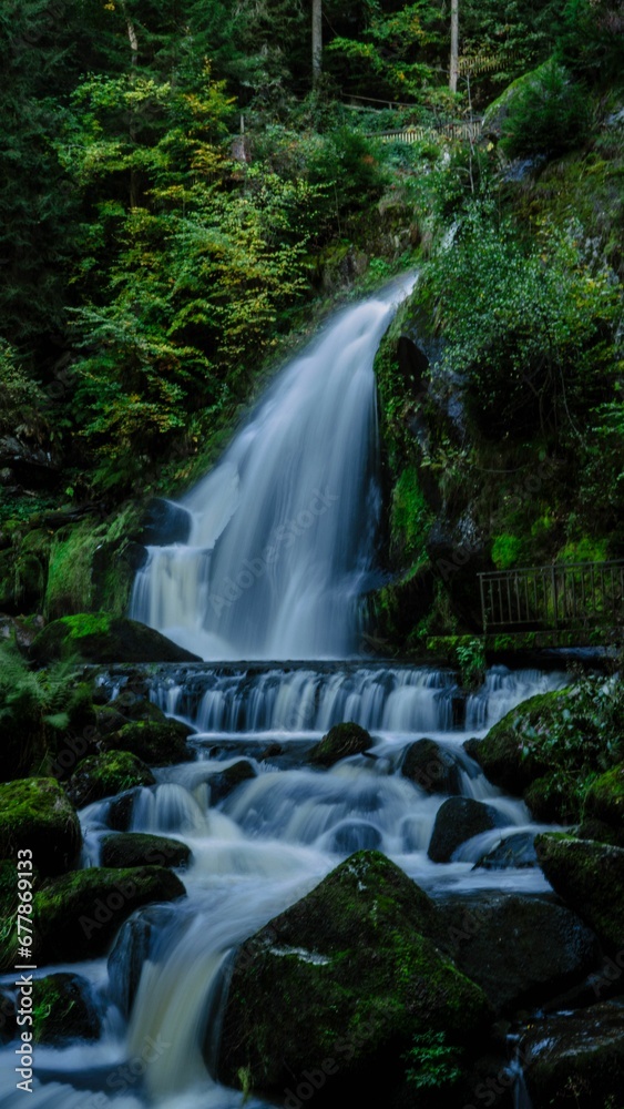 Vertical long exposure view of the scenic Triberg waterfall surrounded by vegetation in Germany