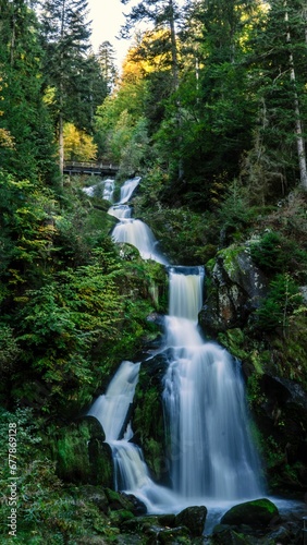 Fototapeta Naklejka Na Ścianę i Meble -  Vertical long exposure view of the scenic Triberg waterfall surrounded by vegetation in Germany