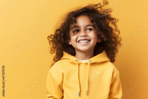 Portrait of a happy smiling curly child girl on yellow background