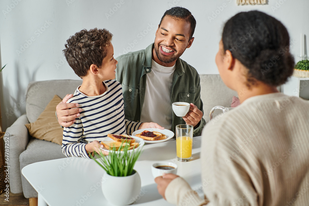 focus on african american father and son smiling at each other with blurred woman looking at them focus on african american father and son smiling at each other with blurred woman looking at them