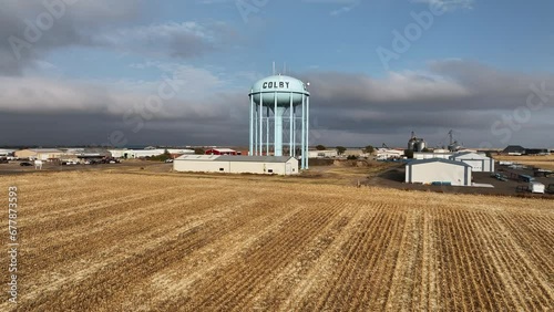 Flying over cut field towards water tower in Colby, Kansas viewing the town sprawled out behind.