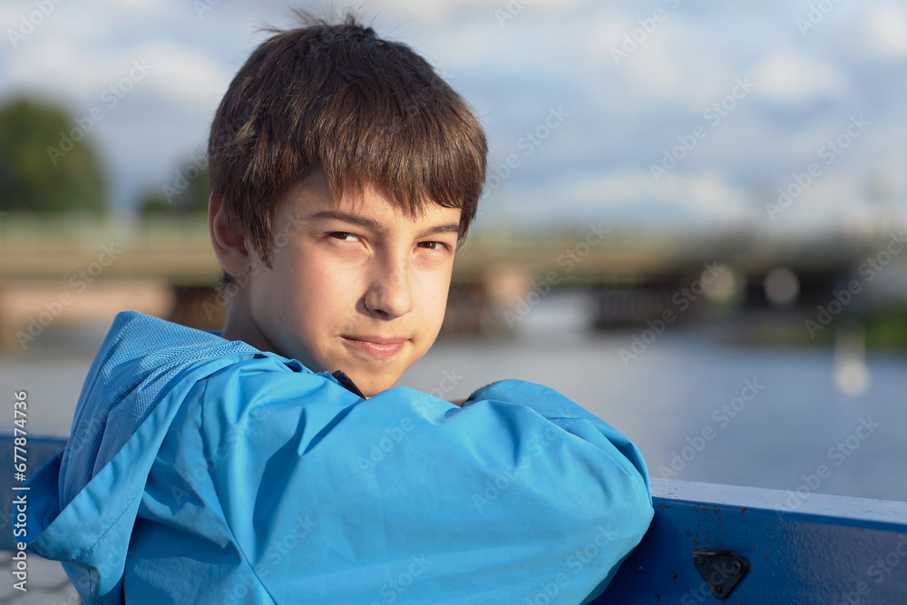 A caucasian boy in a blue jacket on the street A caucasian boy in a blue jacket on the street