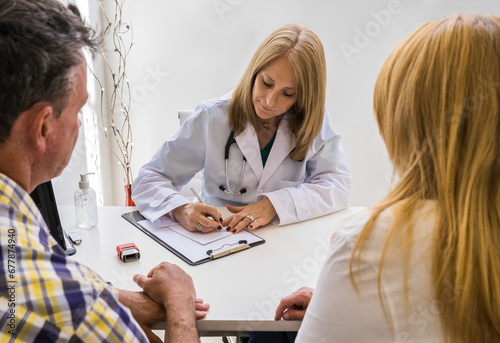 Female doctor writing prescription to a couple photo
