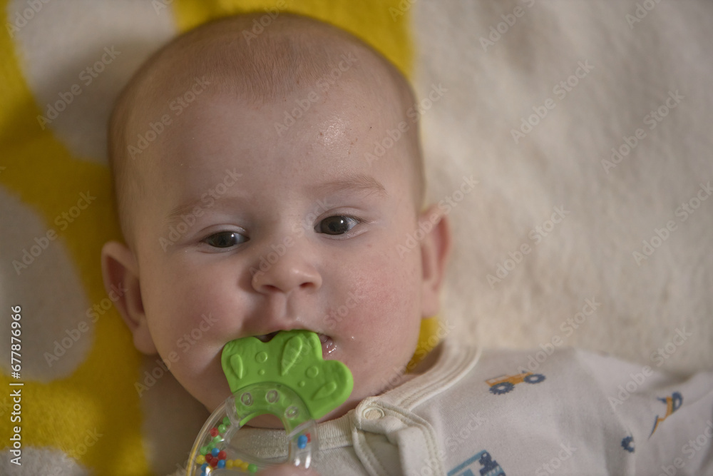 the baby is gnawing a toy lying on the bed, age 5 months. the baby is gnawing a toy lying on the bed, age 5 months.