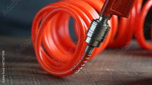 Worker connects orange air hose to air blow gun via hose coupling, closeup. Spiral hose for supplying air pressure to the instrument and possibility of working at a large distance from the main base photo