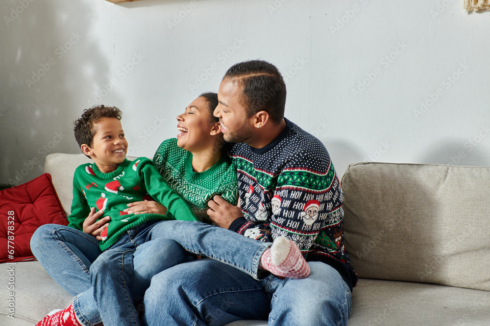 joyous african american parents holding their son on laps smiling happily at each other, Christmas