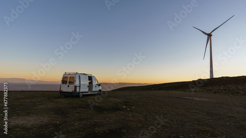 Wind turbine at Serra da Arada over mountain landscape at evening sunset with camper van on road trip, Sao Pedro do Sul, Portugal photo