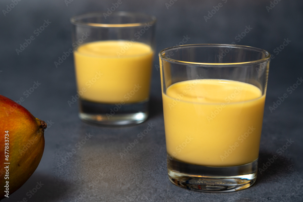 A popular Indian mango drink called lassi, made with mango, yoghurt, milk and sugar, is served chilled  in glass tumblers. Selective focus.