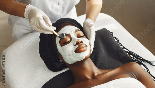 beautiful african woman getting face massage in beauty spa cosmetologist smears nutrient mask in beauty salon face peeling mask spa beauty treatment skincare selfcare concept