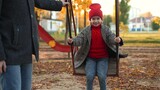 Loving father pushes little daughter on swing with care enjoying time together