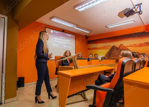 Young university student giving a speech on the podium defending her diploma at the conference room in front of the professors and students