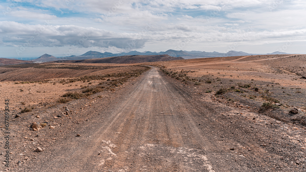Long emplty lonely dirt road long route ahead volcanic lunar landscape no people, lanzarote, canary islands, spain