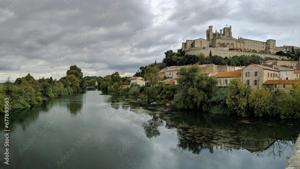 Drone shot of the Cathedral of St. Nazarius on the bank of a river in Beziers, France