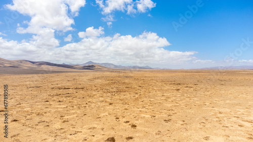 Long emplty lonely dirt road with volcano and red flowers succulent plants desert long route ahead volcanic lunar landscape no people, lanzarote, canary islands, spain photo