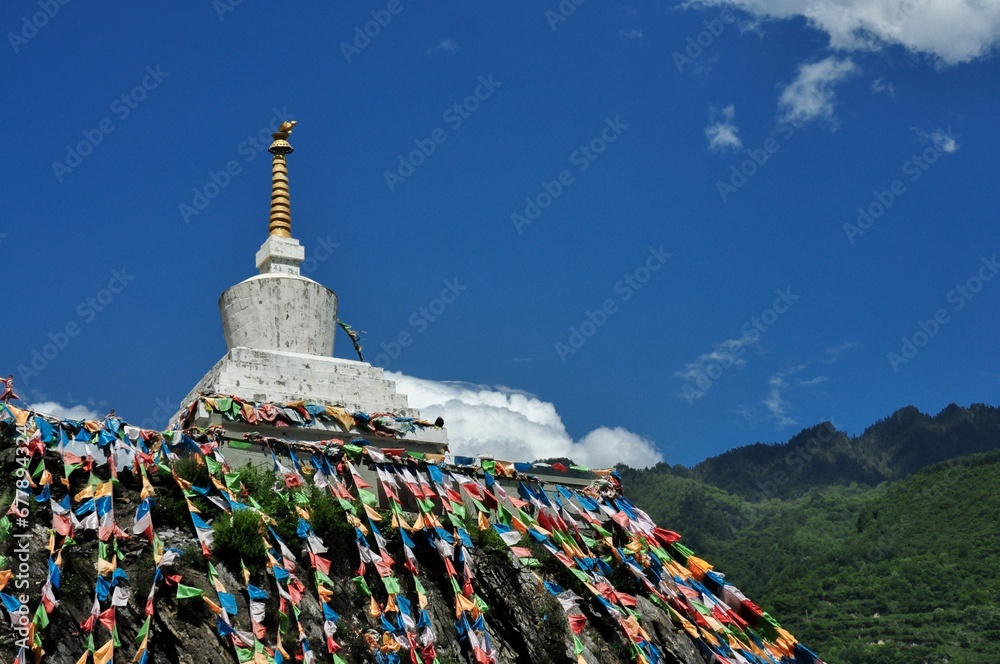 Traditional colorful flags with the symbol of Buddhist stupa on a mountain against blue sky