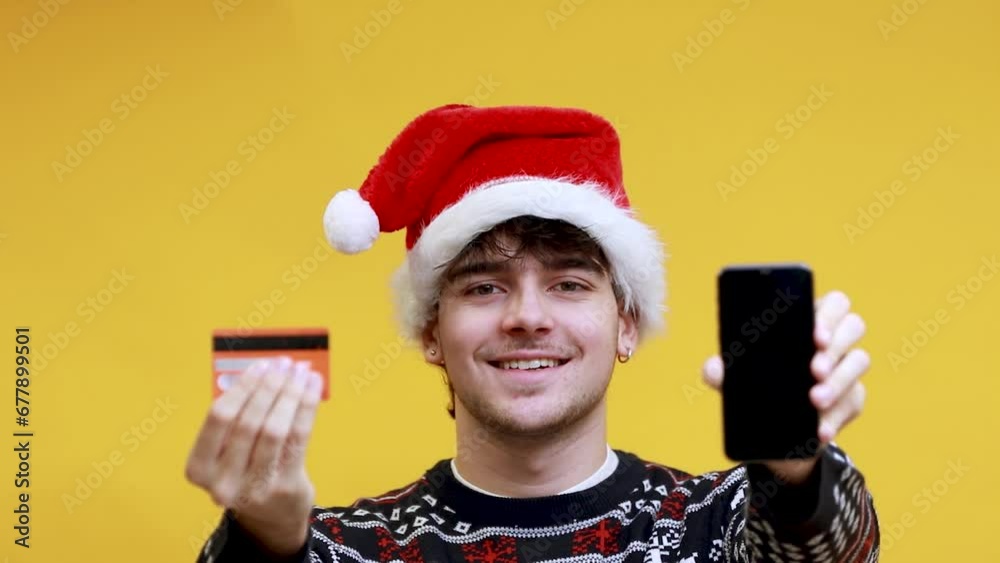 young man with credit card and mobile phone wearing santa claus hat, christmas shopping young man with credit card and mobile phone wearing santa claus hat, christmas shopping