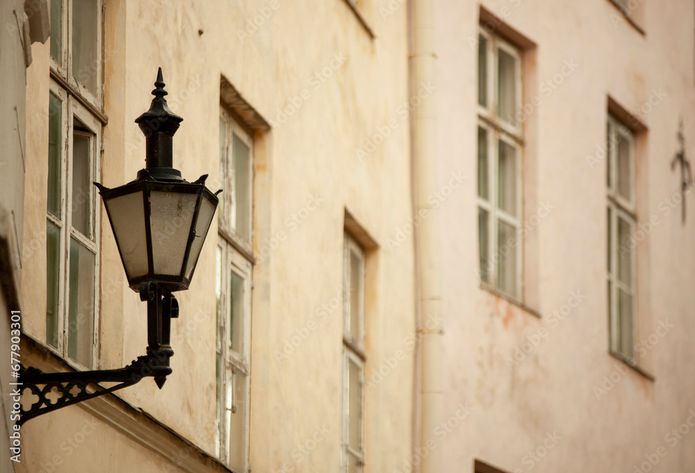An antique street lamp on the wall of a house in the city. Photo