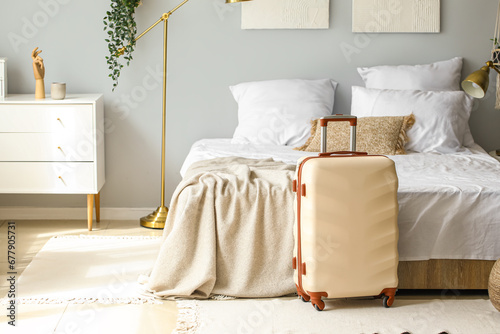 Big suitcase near bed in light room photo