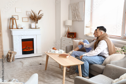 Young couple sitting on sofa near fireplace at home
