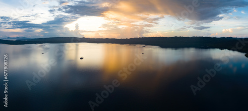 Fototapeta Naklejka Na Ścianę i Meble -  A serene sunrise illuminates the calm seas of Raja Ampat, Indonesia. This remote, equatorial region is known for its high marine biodiversity and is a popular destination for diving and snorkeling.