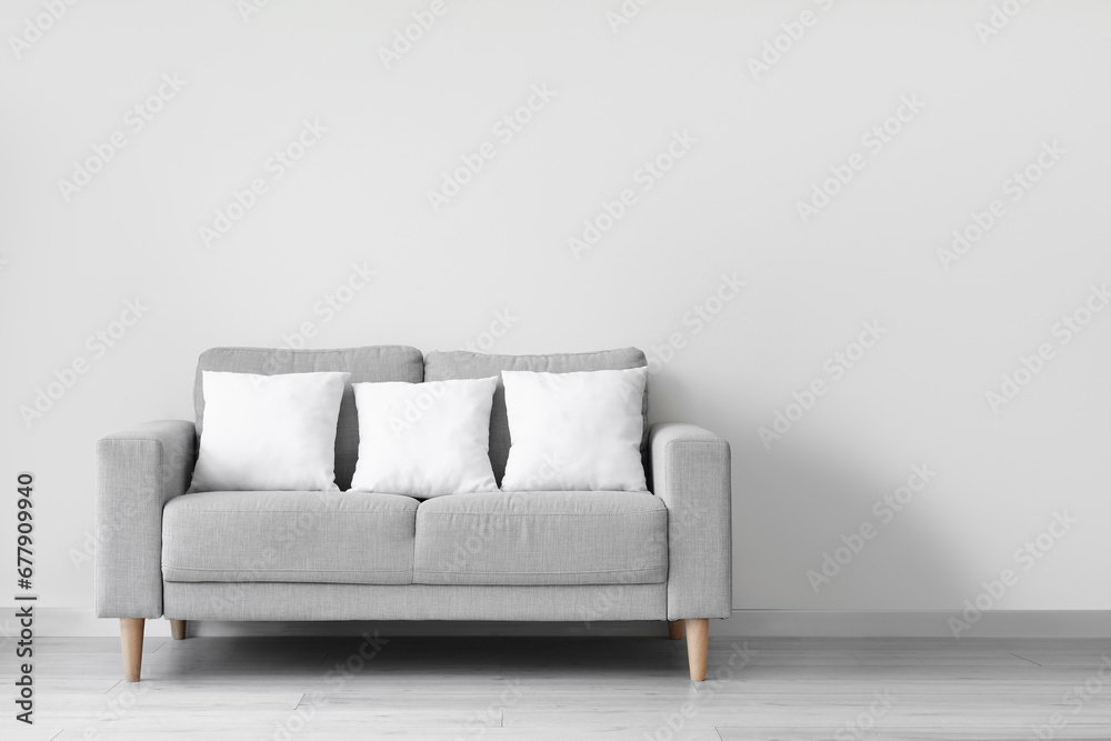Grey sofa with pillows near white wall Grey sofa with pillows near white wall