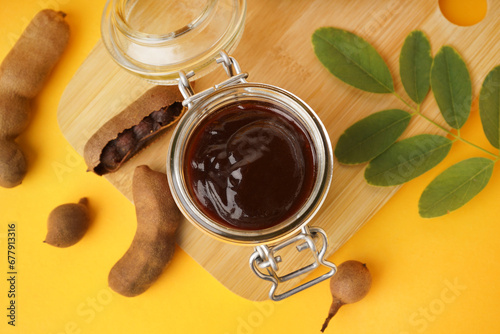 Fototapeta Naklejka Na Ścianę i Meble -  Jar with tasty tamarind jam with fruits on orange background