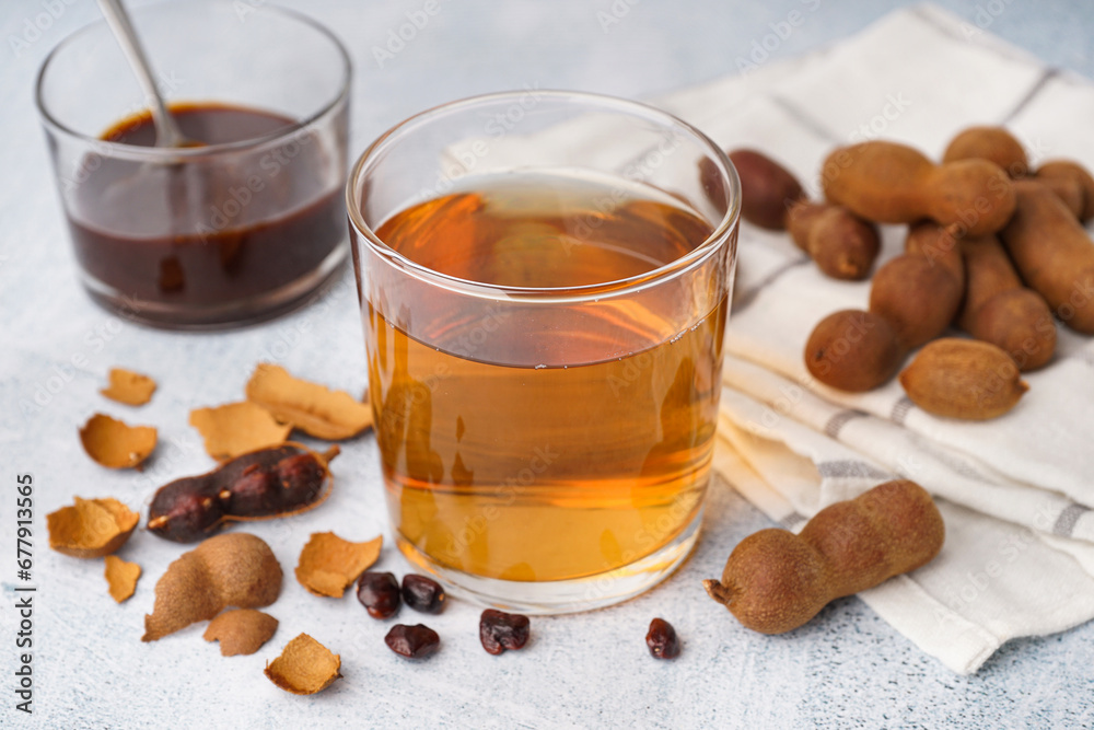 Glass of tasty tamarind drink and fruits on white background