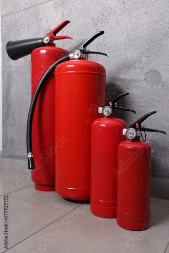 Four red fire extinguishers near grey wall © New Africa