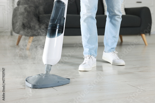 Man cleaning floor with steam mop at home, closeup