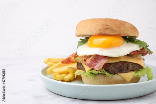 Delicious burger with fried egg and french fries served on white marble table, closeup. Space for text