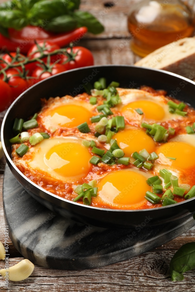 Delicious Shakshuka in frying pan on wooden table, closeup