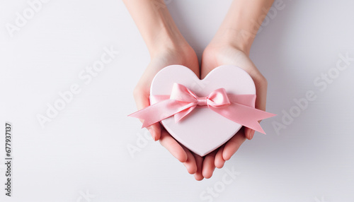 hand holding a white heart box with bow