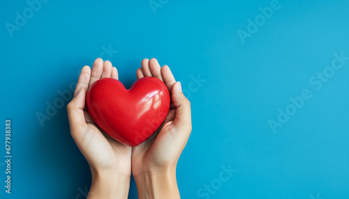 hands holding red heart isolated on blue background with copy space