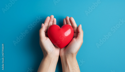 hands holding red heart isolated on blue background with copy space