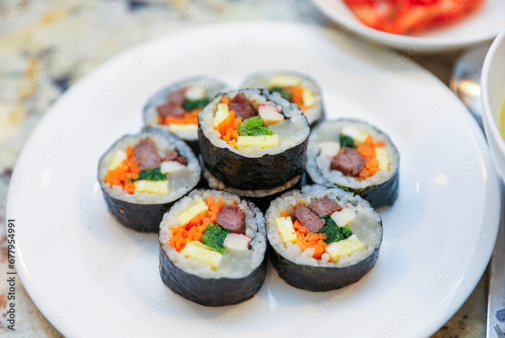 kimbap making, a cherished Korean culinary tradition. Skilled hands roll rice, vegetables, and seaweed, crafting delicious, nutritious bites for an authentic dining experience kimbap making, a cherished Korean culinary tradition. Skilled hands roll rice, vegetables, and seaweed, crafting delicious, nutritious bites for an authentic dining experience