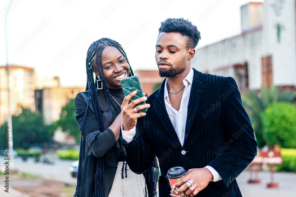 two business employees male and female both smiling looking at a cellphone two business employees male and female both smiling looking at a cellphone