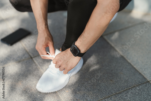 Preparation before jogging. Closeup hand of athletic male tying shoelace on running shoes. Fitness and sport activity. Healthy exercise concept.