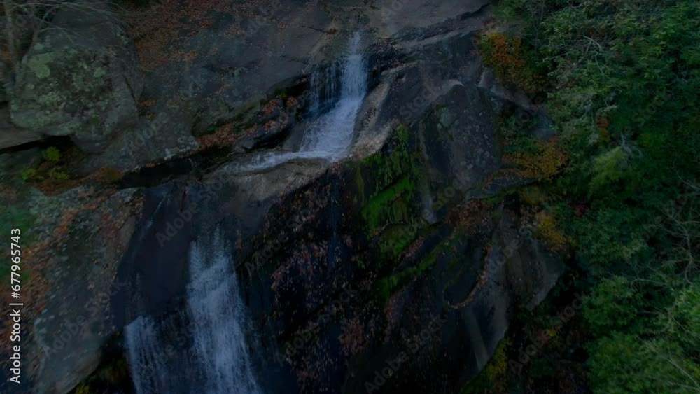 Drone flying over a massive waterfall in the mountains of autumn colors in the afternoon. Drone flying over a massive waterfall in the mountains of autumn colors in the afternoon.