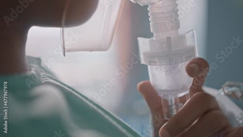 Asian girl having an oxygen mask and breathing through a nebulizer at the hospital.