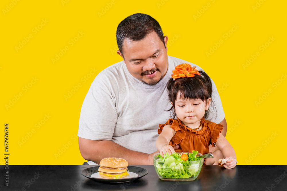 Cute little girl with father chooses a bowl of salad over hamburger Cute little girl with father chooses a bowl of salad over hamburger