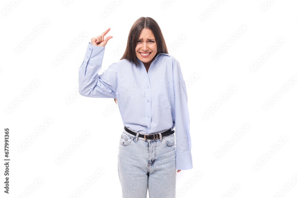 pretty young brunette european woman dressed in a blue shirt points with her hands towards an object on an isolated background with copy space