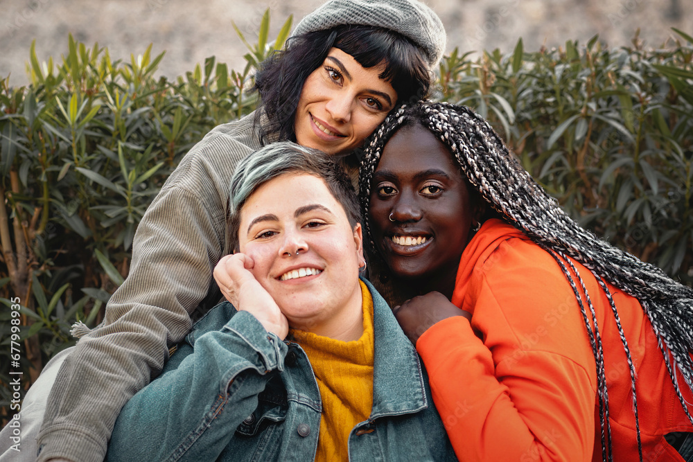 Three close friends share a warm embrace, showcasing their unique styles and joyful smiles against a natural backdrop. Three close friends share a warm embrace, showcasing their unique styles and joyful smiles against a natural backdrop.