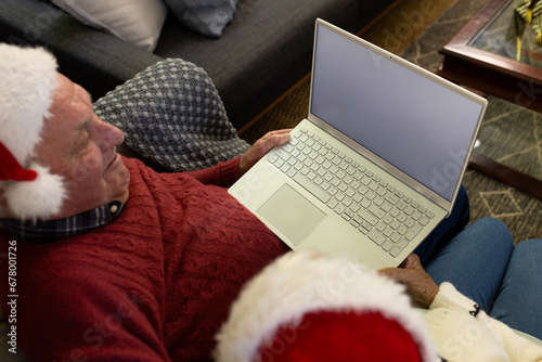 Happy caucasian senior couple in santa hats having christmas laptop video call, copy space on screen