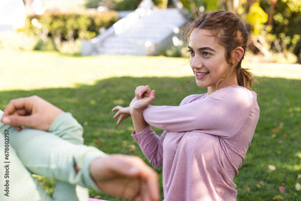 Happy biracial lesbian couple practicing yoga sitting stretching in sunny garden Happy biracial lesbian couple practicing yoga sitting stretching in sunny garden