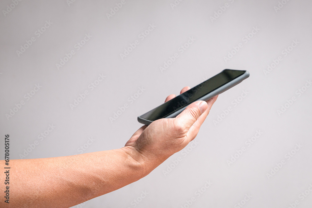 Man hand holding a phone, side view. On off white background, copy space. Man hand holding a phone, side view. On off white background, copy space.