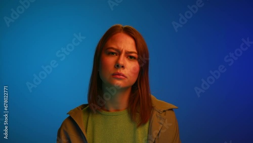 Portrait of Young Woman Looking at Camera with Thinking Face Closeup. Doubting 20s Lady at Neon Shot Considering Thoughts of Work Plans or Brooding on Life Choices. Female Model Listening to Hard Talk