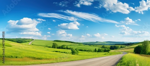 Country road in green field and blue sky with clouds. Panoramic view. photo