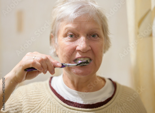 Aged woman brushes her teeth.